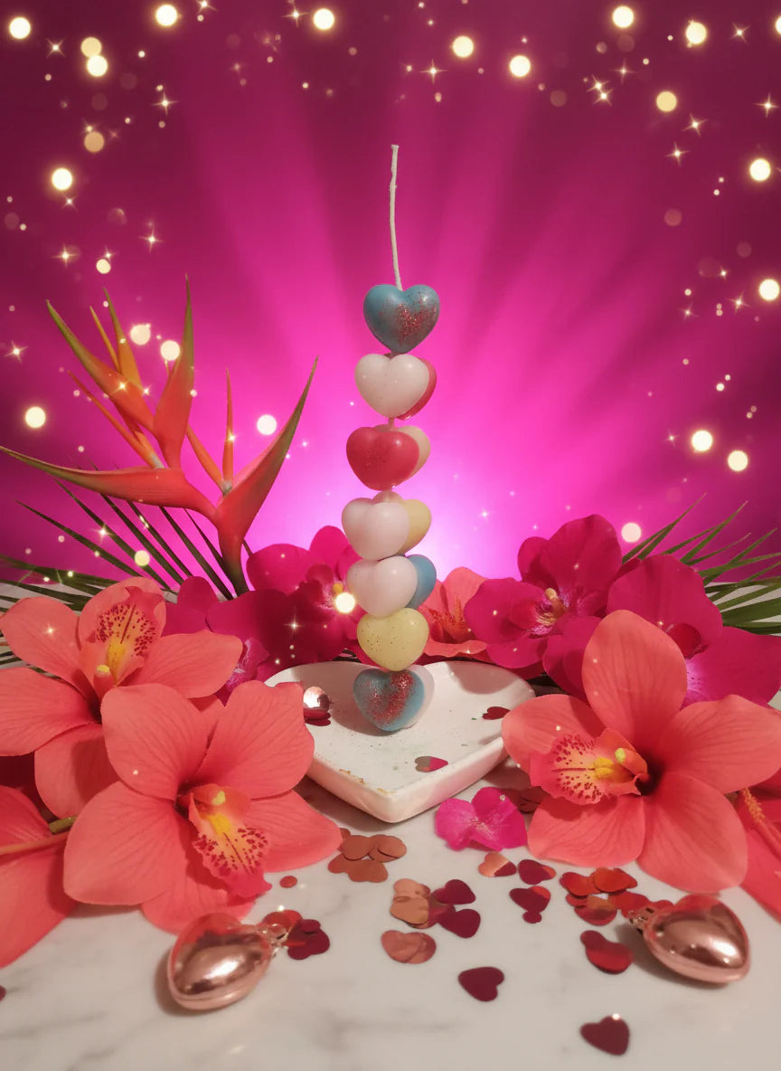 Decorative vertical heart candle arrangement on a pink background.